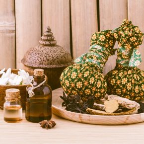 Natural Spa Ingredients herbal compress ball and essential Oil for alternative medicine and relaxation Thai Spa theme with bamboo background.