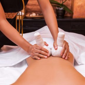 Woman getting thai herbal ball massage treatments in spa.